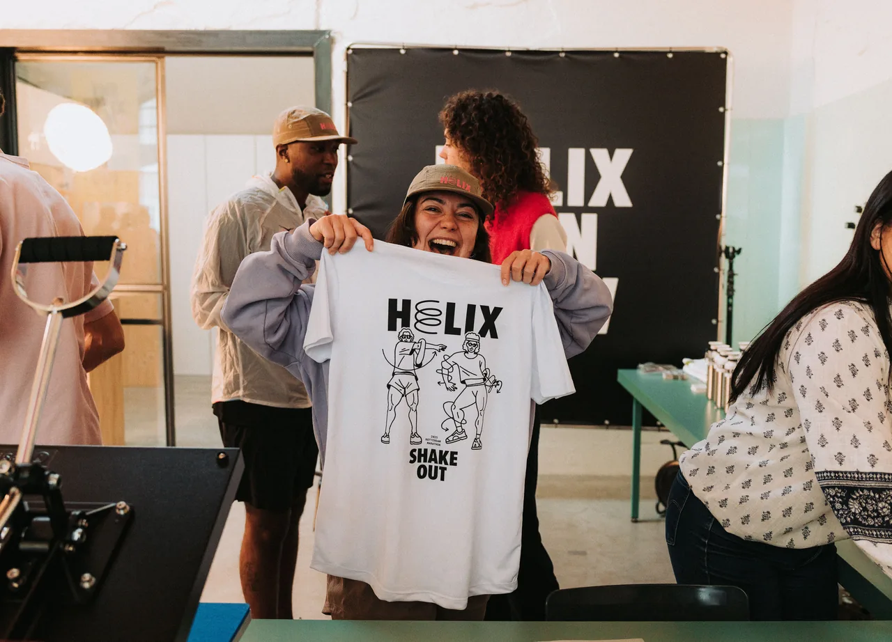 A smiling member holding up a Helix “Shake Out” race tee